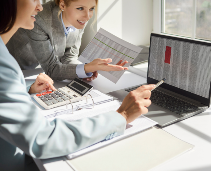 two women looking at a spreadsheet on a computer screen